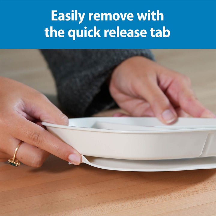 A close-up of a person's hands removing a gray No-Slip Divided Suction Plate from a base, with a blue text banner at the top that reads 'Easily remove with the quick release tab.'.