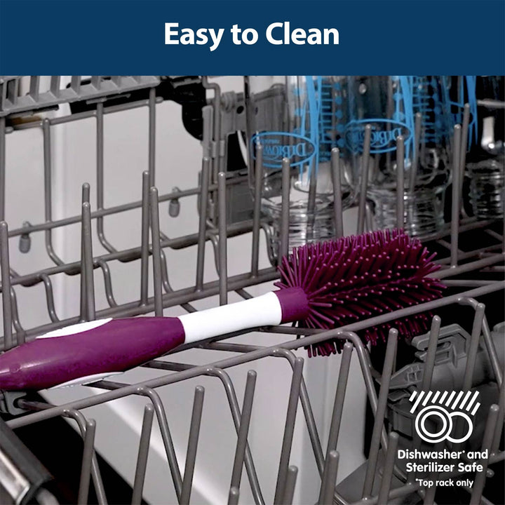 A dark pink and white dishwashing brush resting on a gray dishwasher rack, with a dark blue banner at the top reading 'Easy to Clean' and a dishwasher/sanitizer-safe badge in the lower right.