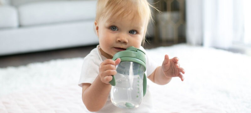 Baby's 1st Straw Cup lifestyle image of a baby drinkgin from a green Dr. Brown's Straw Cup