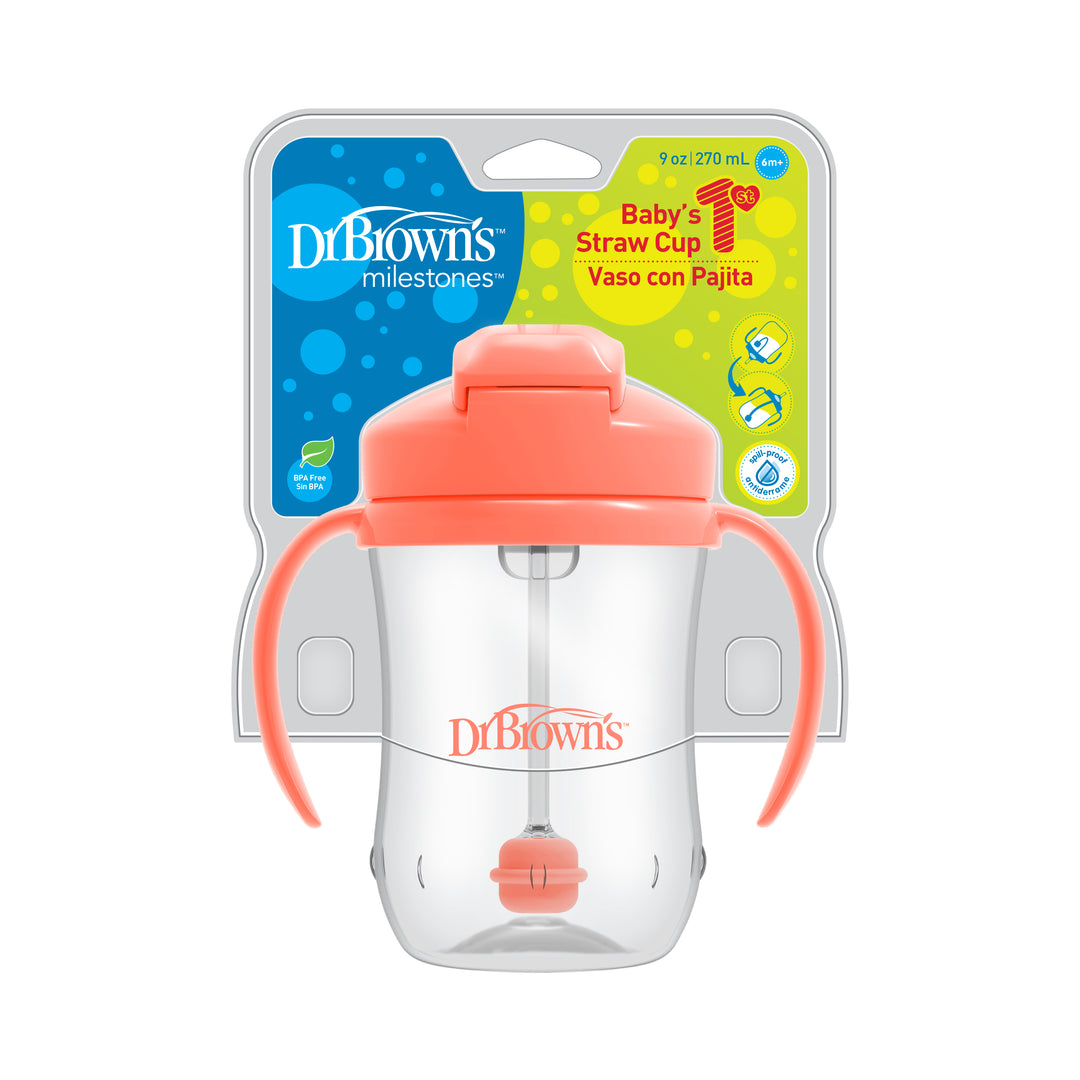 Introducing the Dr. Brown’s™ Milestones™ Baby’s First Straw Cup, perfect for transitioning your baby from bottle to cup. This clear cup with a coral lid and handles incorporates a weighted straw design for effortless sipping. The packaging displays its 9 oz (270 ml) capacity with text in both English and Spanish.