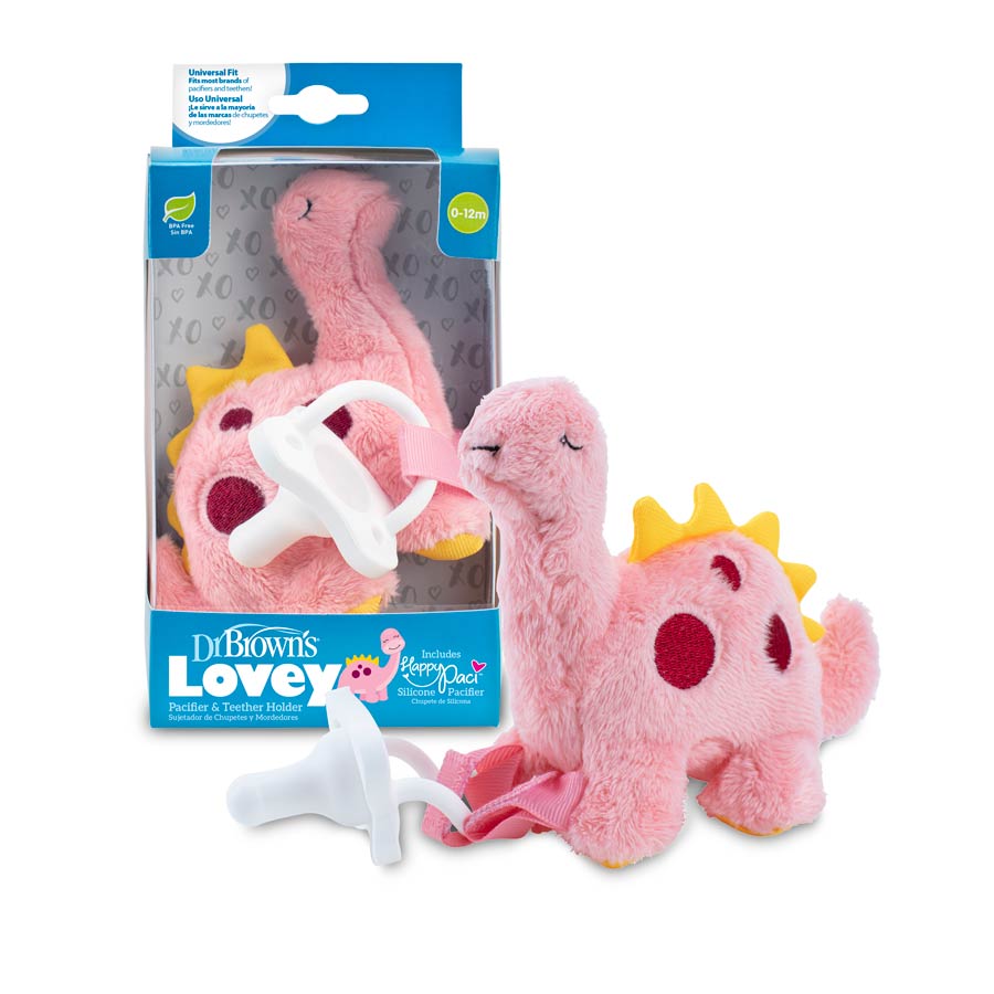 A cuddly pink dinosaur adorned with yellow spikes and red spots, clutching a pacifier, comes packaged in a box labeled "Dr. Brown’s® Lovey Pacifier and Teether Holder, Dinosaur." This charming plush toy serves as both a pacifier and teether holder, ideal for infants aged 0-12 months.