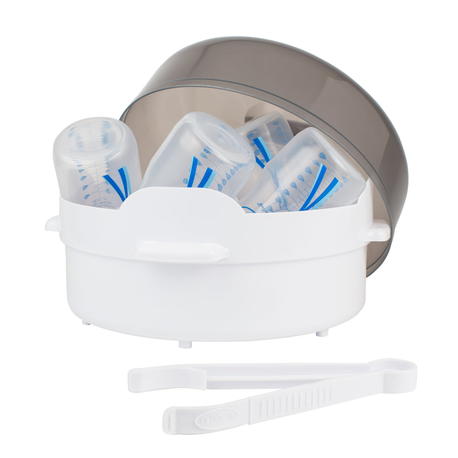 The Dr. Brown's Baby Bottle Microwave Steam Sterilizer, featuring a translucent lid and blue markings, accommodates multiple baby bottles. White plastic tongs are conveniently placed in front, and side handles are designed for easy carrying.