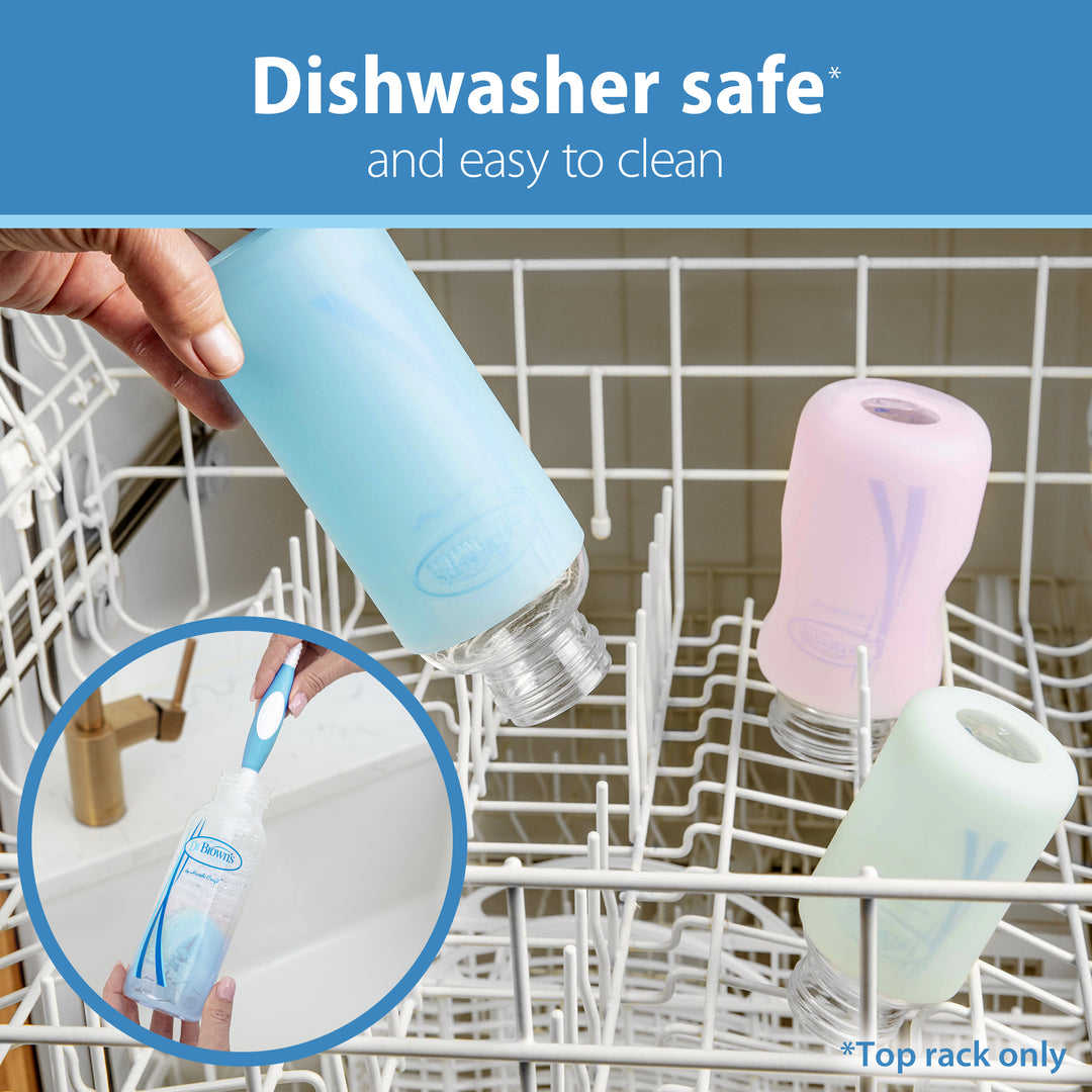 Dr. Brown's Natural Flow® Anti-Colic Options+™ Narrow Baby Bottles, featuring the Level 1 Slow Flow Nipple, are positioned on the top rack of a dishwasher. A close-up image reveals a hand cleaning one of the bottles with a brush. Text emphasizes that these Dr. Brown's bottles ensure natural flow, are dishwasher safe, and easy to clean.