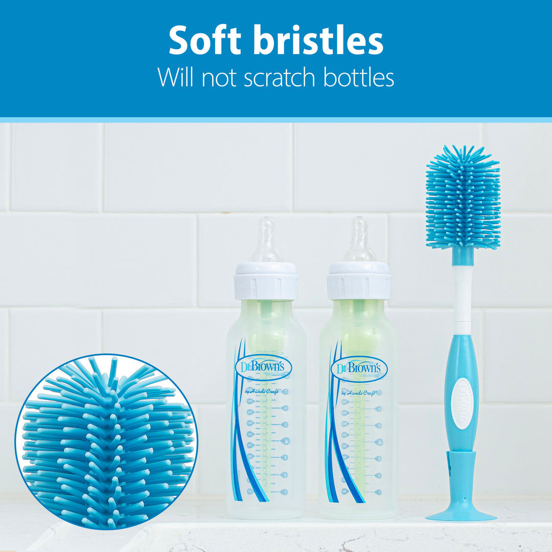 Visual of two baby bottles beside Dr. Brown's™ Soft Touch Bottle Brush, specifically crafted for scratch-free cleaning. The blue and white bottle brush is positioned upright on a kitchen counter. At the top, the text states, "Soft bristles will not scratch bottles.