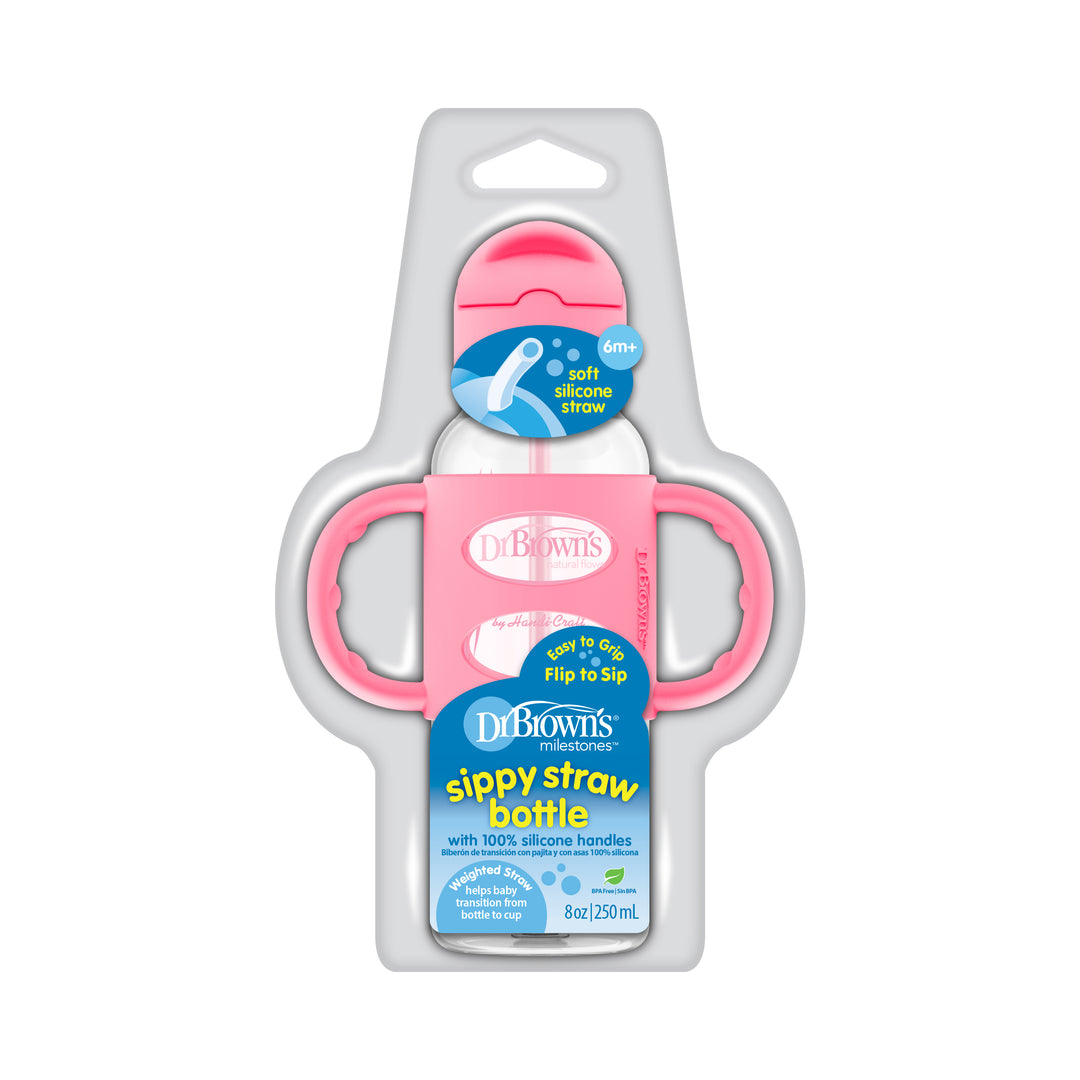 The packaging of Dr. Brown’s™ Milestones™ Narrow Sippy Straw Bottle with Silicone Handles, 8 oz/250 mL, highlights its pink handles and cap. Equipped with a flip-to-sip lid and a silicone weighted straw, it is ideal for fostering independent drinking skills in children aged 6 months and older.