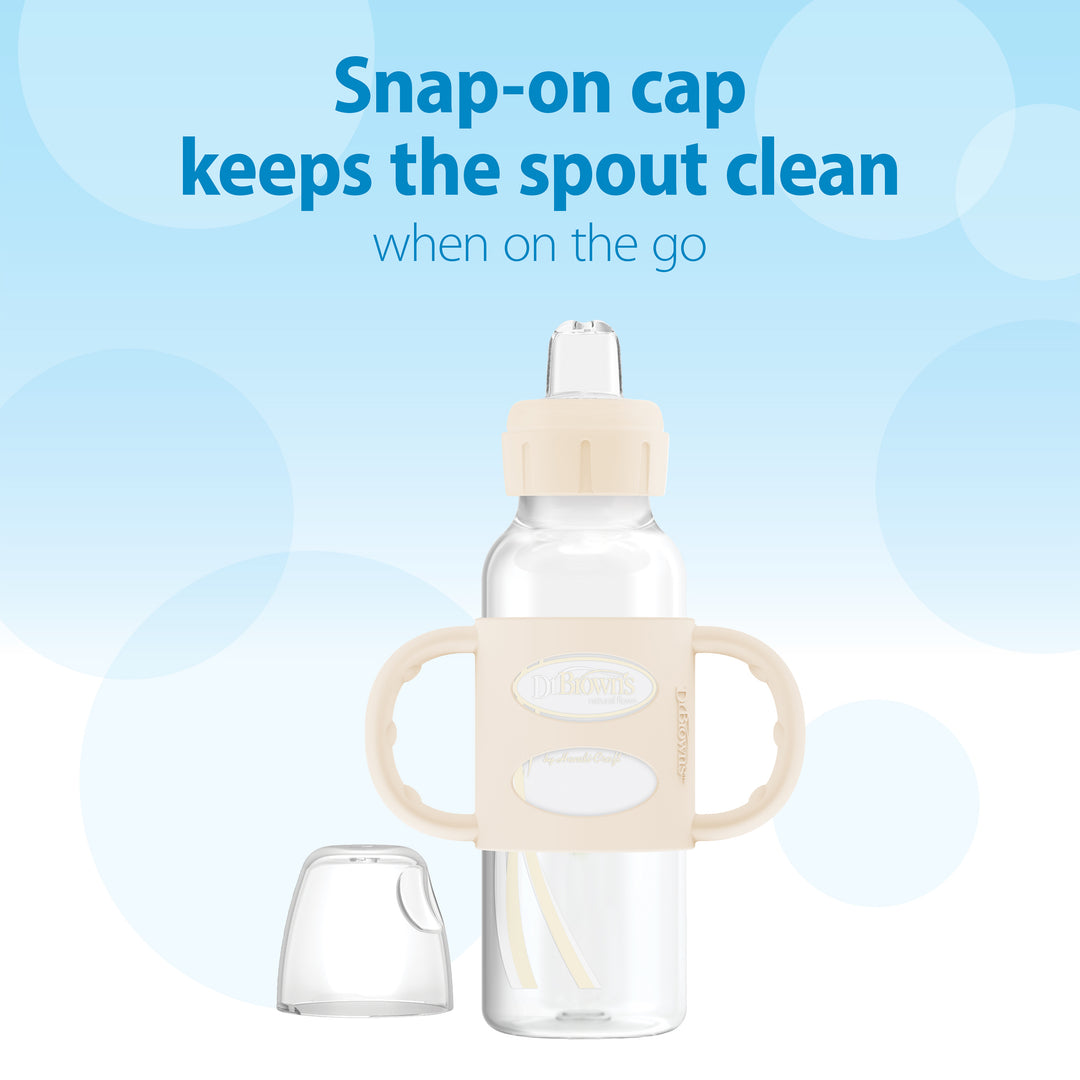 A Dr. Brown's Milestones™ Narrow Sippy Spout Bottle with beige silicone handles and a snap-on cap is displayed against a blue gradient background. The text reads, "Snap-on cap keeps the sippy spout clean when on the go." The bottle features a designated clear section for storing the cap on its side.