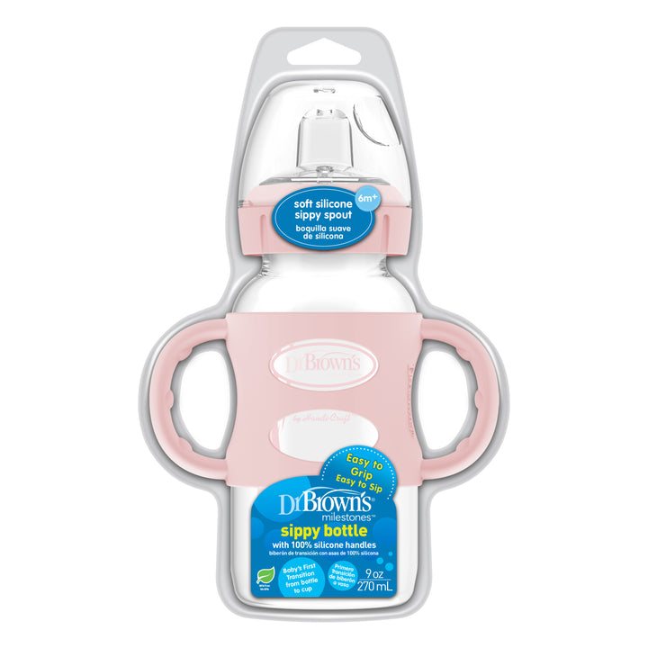 Image of a Dr. Brown’s® Milestones™ Wide-Neck Sippy Spout Bottle with Silicone Handles in pink packaging. This bottle includes a soft silicone spout and ergonomic silicone handles, holding 9 oz/270 mL. The label emphasizes its BPA-free construction and easy-grip design, ideal for children aged 6 months and older to ease the transition to independent drinking.