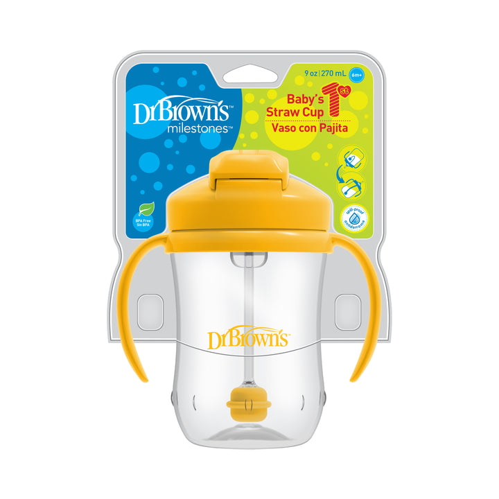 The packaging displays a spill-proof baby straw cup featuring handles and a yellow lid. This 9 oz (270 ml) cup, called "Dr. Brown’s™ Milestones™ Baby’s First Straw Cup," is designed to ease the transition from bottle to cup and is labeled as "Baby's Straw Cup" in both English and Spanish.