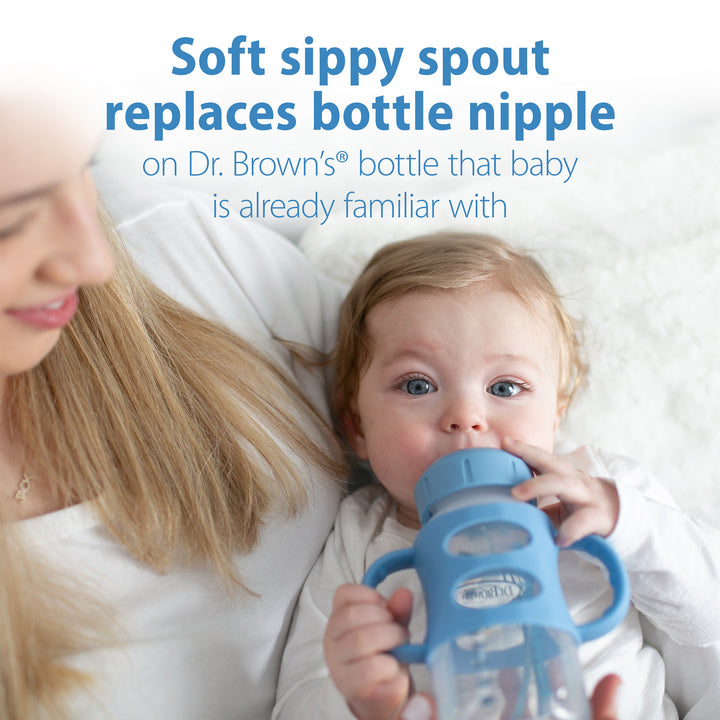 A woman cradles a baby who drinks from a Dr. Brown’s® Milestones™ Wide-Neck Sippy Spout Bottle with Silicone Handles, 9 oz/270 mL. The text above reads, "The silicone sippy spout smoothly transitions your baby's favorite Dr. Brown's bottle.