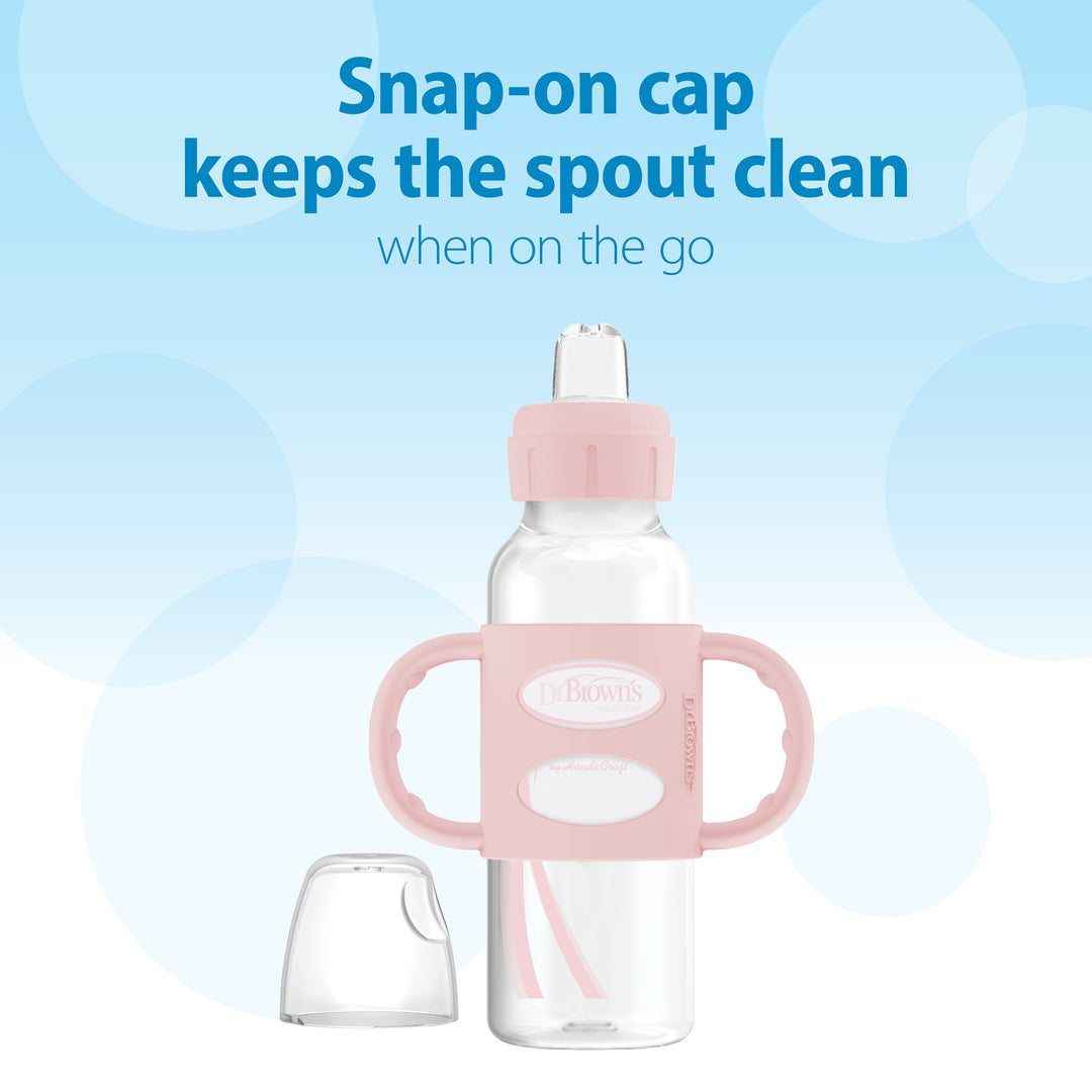 Dr. Brown’s® Milestones™ Narrow Sippy Spout Bottle, featuring silicone handles and a pink snap-on cap with a spout, includes a removable clear plastic cover. The light blue background showcases the message: "Snap-on cap keeps the sippy spout clean when on the go.