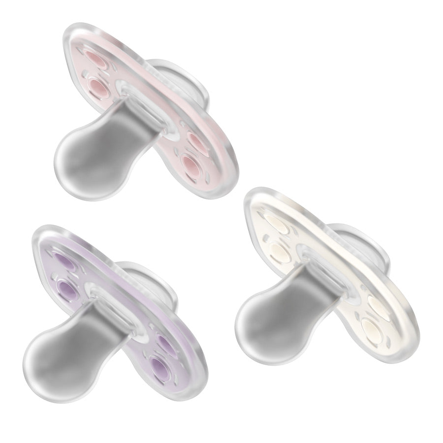 A set of three Dr. Brown's Advantage One-Piece Silicone Pacifiers is displayed in a triangular formation, each featuring a translucent design in hues of pink, purple, and white. These pacifiers have soft, rounded teats that are gentle against the baby's skin and are presented on a plain white background.