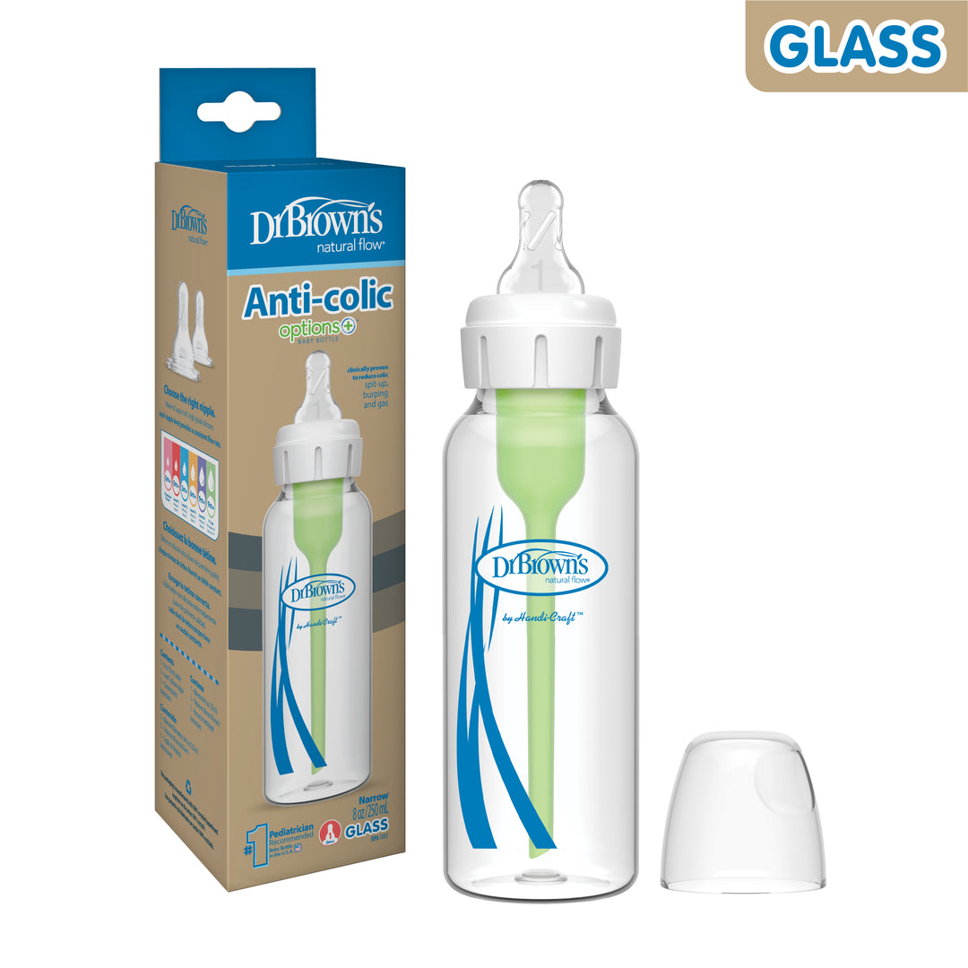 A Dr. Brown’s Natural Flow® Anti-Colic Options+™ Narrow Glass Baby Bottle, featuring a Level 1 Slow Flow Nipple and green vent system, is displayed next to its packaging. The bottle highlights its brand "Dr. Brown's" with natural flow and anti-colic features, accompanied by a clear cap placed beside it.