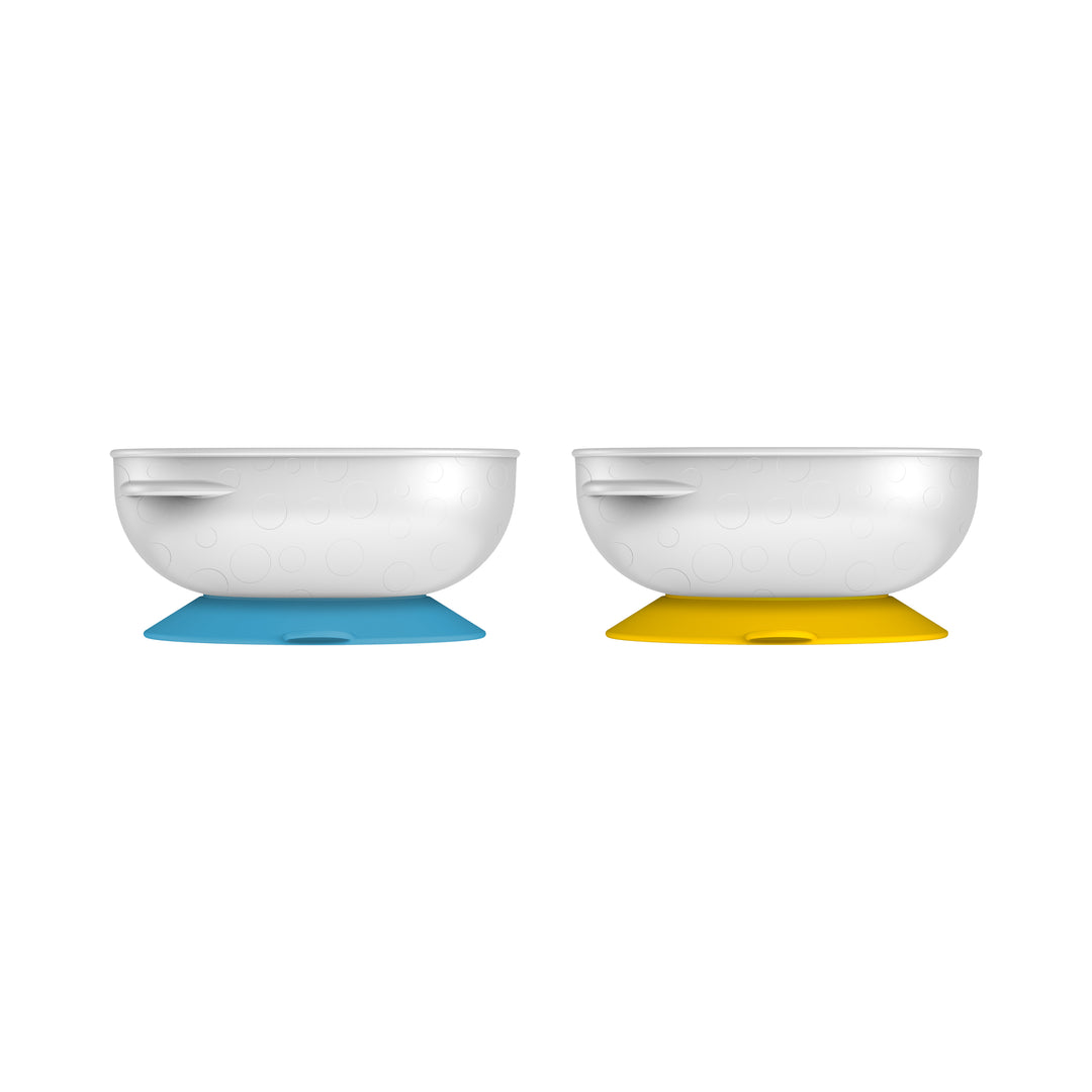 The Dr. Brown's™ No-Slip Suction Bowl, 2-Pack includes two white bowls with convenient side handles for promoting independent eating skills, each securely perched on suction bases. One bowl features a blue base and the other a yellow, set against a simple white background, making them the perfect addition to baby's mealtime with both ease and style.