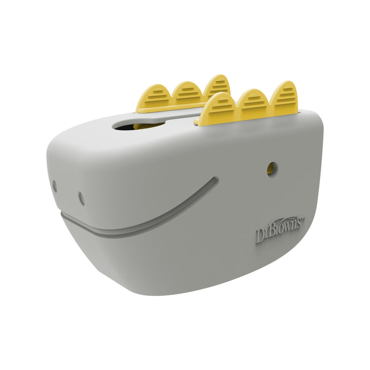 A gray safety device shaped like a dinosaur with a smiling face and yellow accents on top, designed for safe bath time as an adjustable faucet cover. The Dr. Brown’s™ CleanUp™ Dino-Soft Baby Bath Spout Cover is perfect for protecting little ones during bath time, with the brand name "Dr. Brown's" embossed on the side.