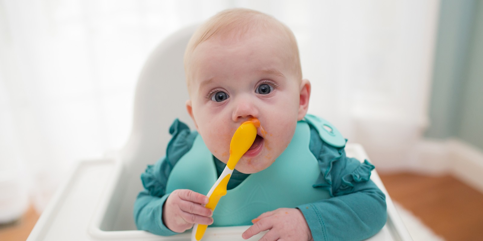 https://www.drbrownsbaby.com/wp-content/uploads/2020/04/4-30-20-Baby-holding-spoon-eating-with-bib-on-Solid-Feeding-Stages-Guide-for-Babies.jpg
