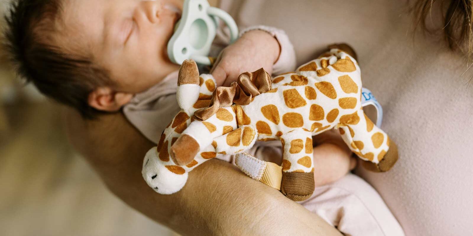 Baby with green HappyPaci and Giraffe Lovey