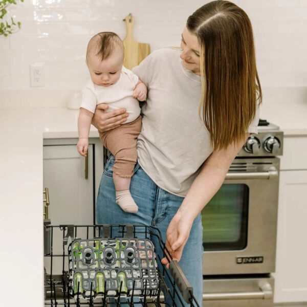 Parent and infant looking at dishwasher with black dishwasher basket